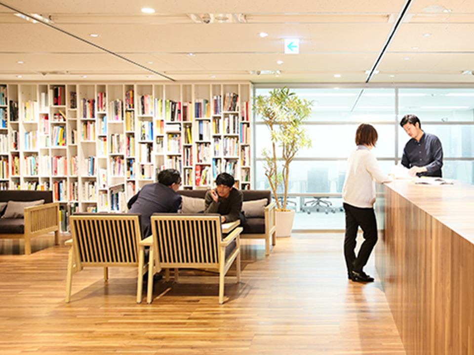 本棚のある明るいオフィス空間で人々が交流する様子